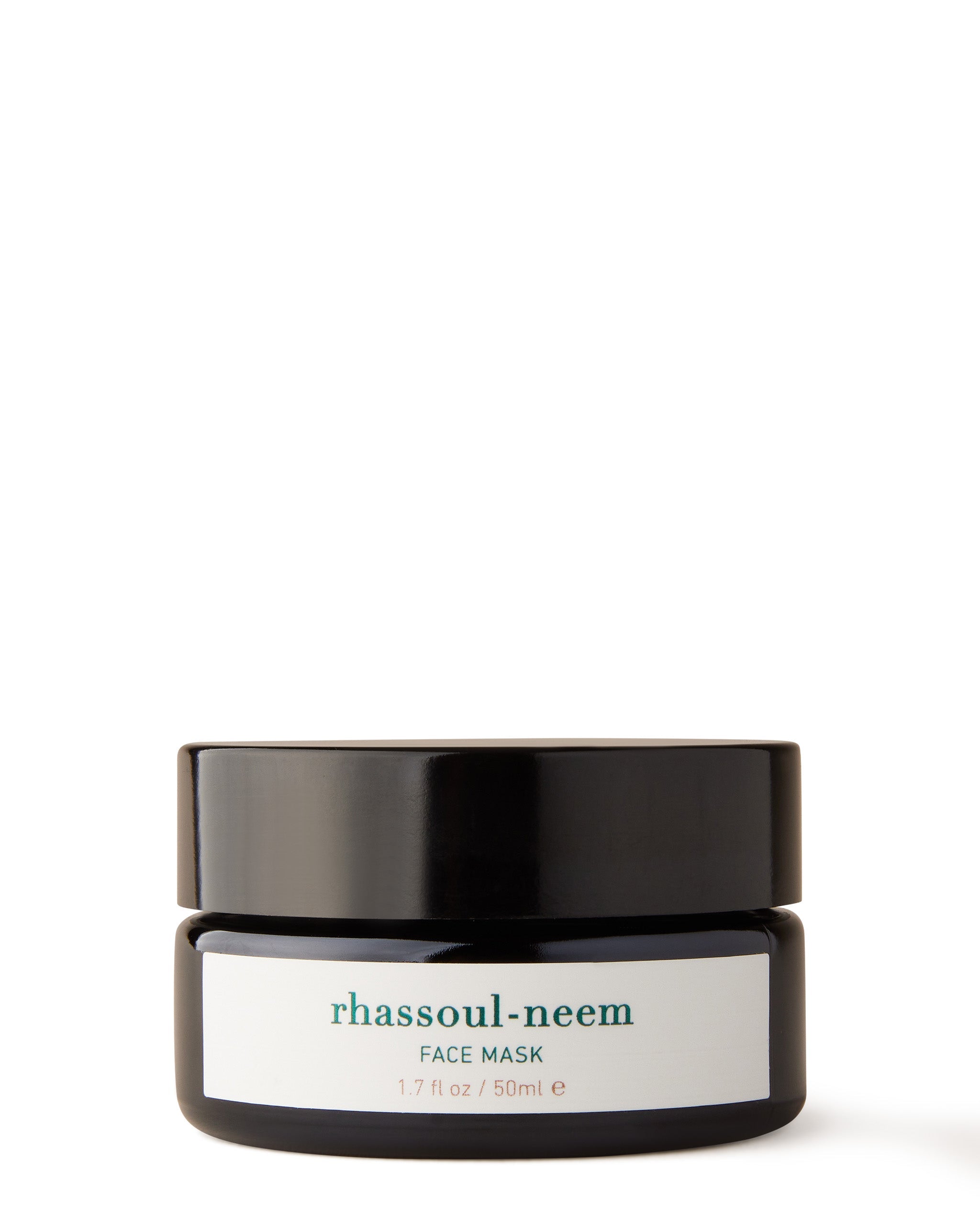 A jar of Rhassoul-Neem Face Mask with a label that includes the product name and a brief description.